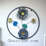 Round Metal Floral Wall Decor with blue and black flowers and gold centers inside a black frame.