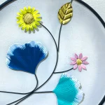 Close-up of Colorful Floral Metal Wall Decor showing yellow, pink, blue, and teal flowers with gold accents.