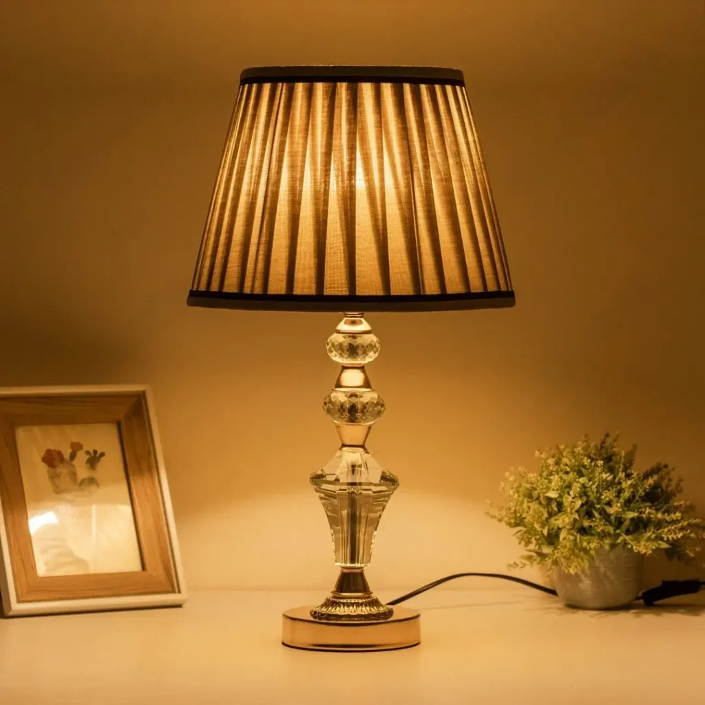 Decorative crystal lamp on white table next to photo frame and plant
