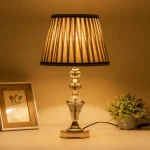 Decorative crystal lamp on white table next to photo frame and plant